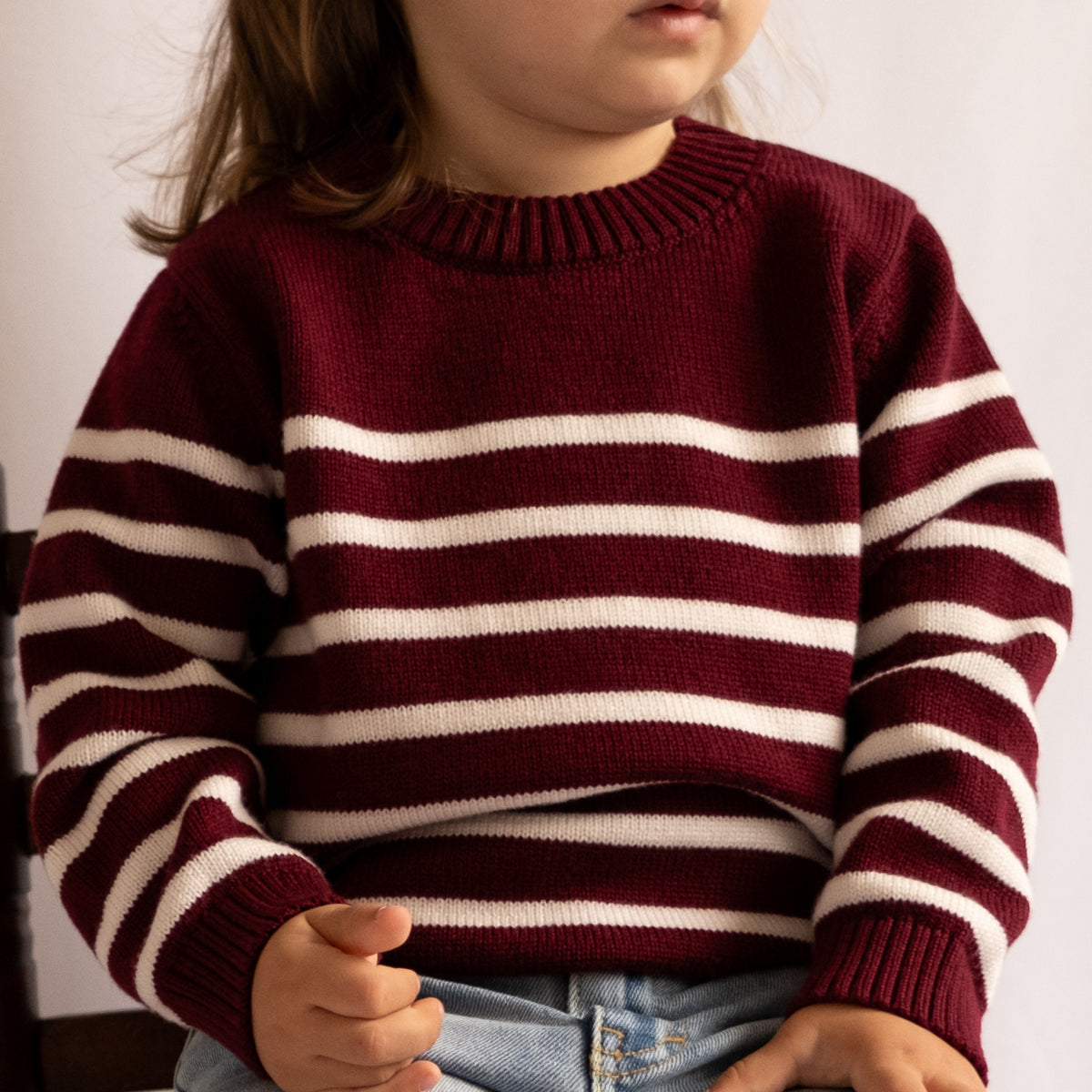 Little girl wearing Breton striped sweater in off white and dark red 